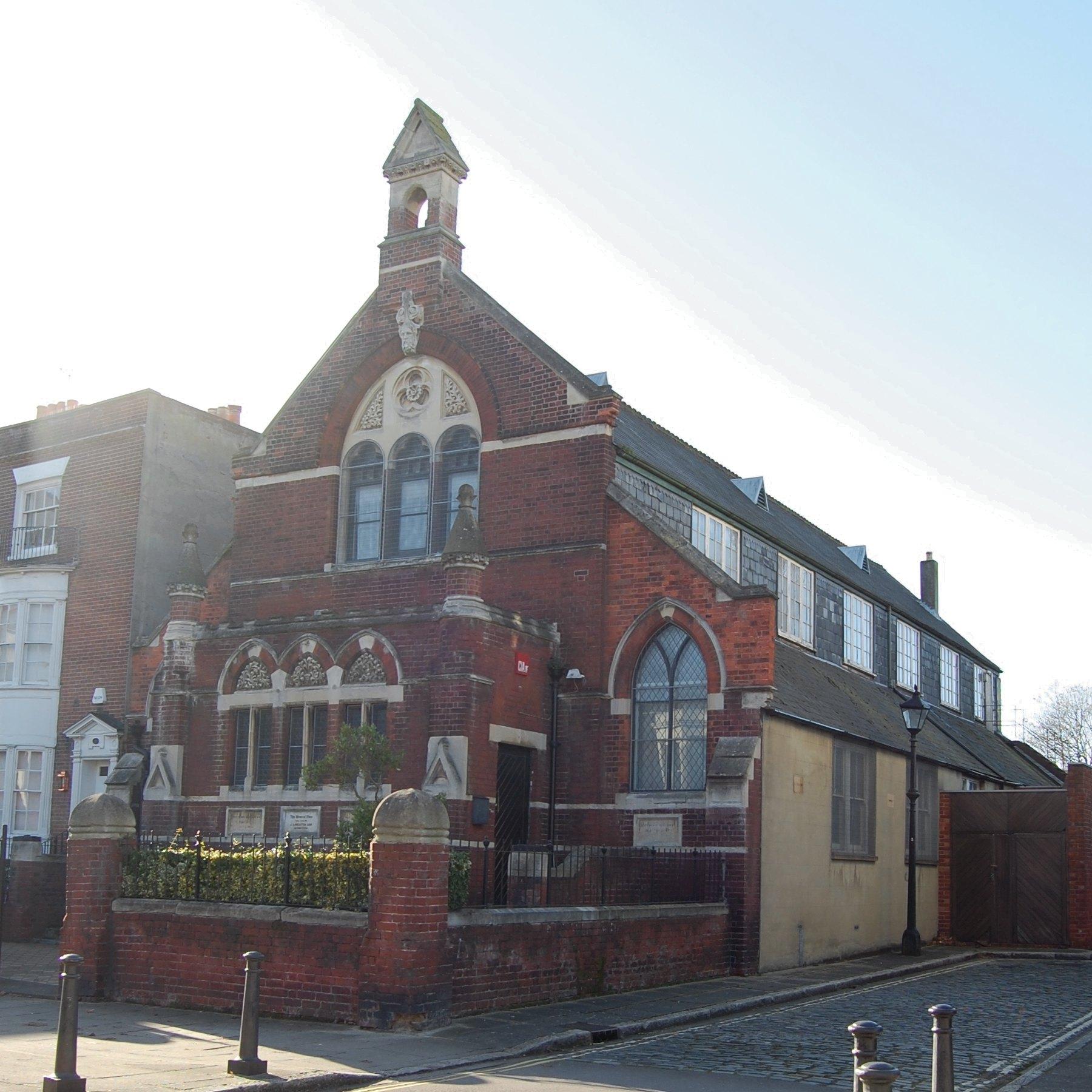 The chapel seen from the street corner, its bell turret against a pale sky