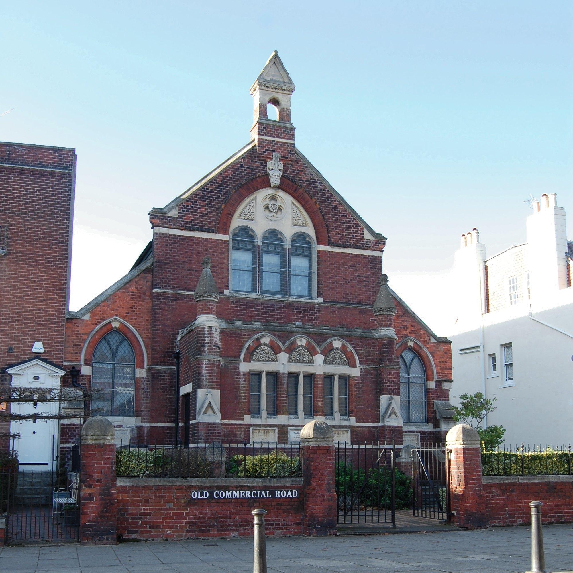 The red brick masjid on Old Commercial Road, its bell turret against a clear sky